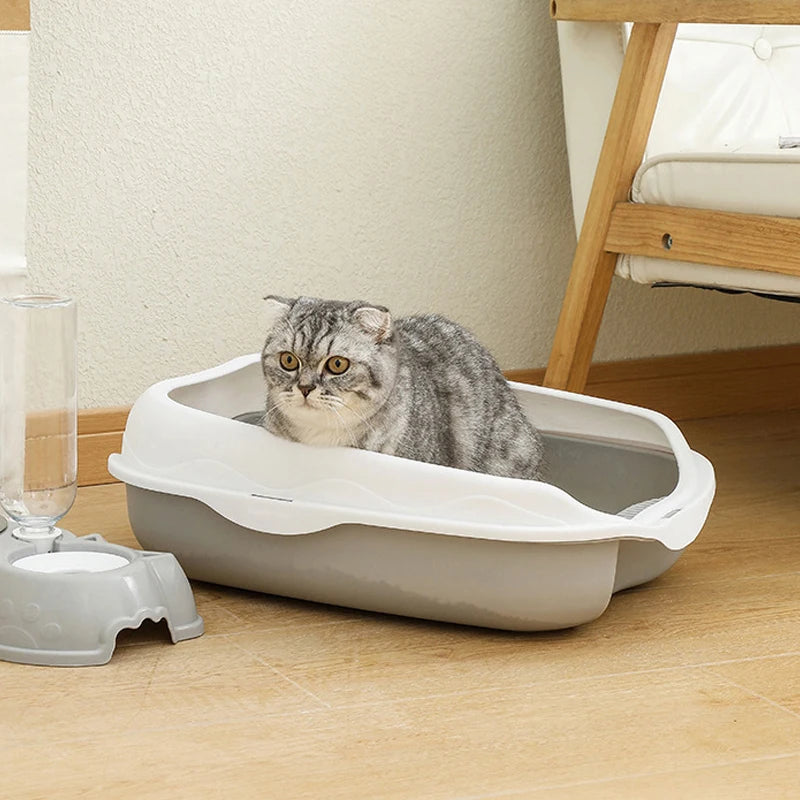 Katze sitzt in grauer halbgeschlossener Toilette